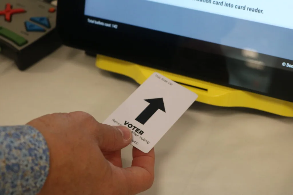 An election worker in Gwinnett County demonstrates a ballot-marking device